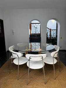 a dining room with a glass table and white chairs at Casa da Tia Iche in Espirito Santo Do Pinhal