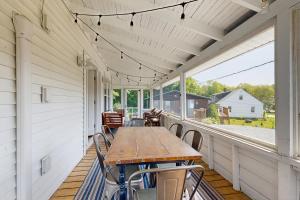 a porch with a wooden table and chairs on it at Bay Cottage in Boothbay Harbor