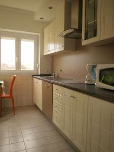 a kitchen with white cabinets and black counter tops at Apartments Nadia2 in Baška