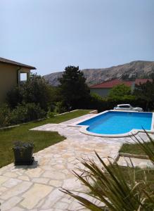 a swimming pool in a yard with mountains in the background at Apartments Nadia2 in Baška