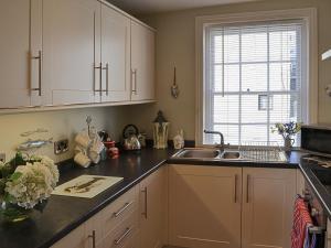 a kitchen with white cabinets and a sink and a window at Rosie's Retreat in Whitby +6 photos
