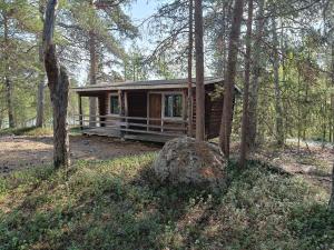 a small log cabin in the woods with a tree at Lomakylä Lapponia in Inari