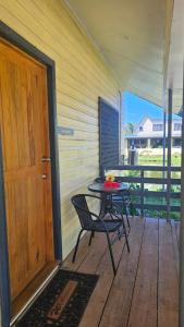 a wooden porch with a table and a door at Queens Inn Studio Apartments in Pacific Harbour