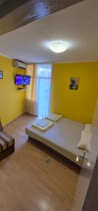 ein Schlafzimmer mit einem Bett mit gelber Wand in der Unterkunft Stan - centar Igalo in Igalo + 6 Fotos