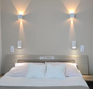 two lights above a bed with white sheets and pillows at Gardenia Sea Side MARTINA 1 Dziwnów in Dziwnów