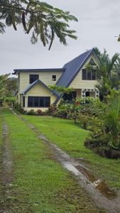 a house with a grass yard in front of it at Queens Inn Studio Apartments in Pacific Harbour