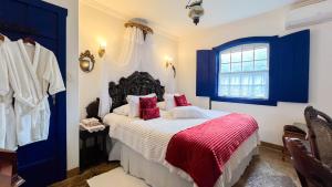 a bedroom with a bed with red pillows and a window at Segredo da Serra Pousada Boutique in Tiradentes