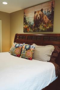 a bed with pillows and a painting of a bear at Lakeshore Lodging Apartment G in Homer