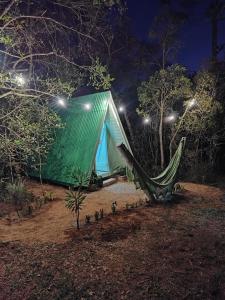 a tent with a hammock in a forest at night at Cachoeira da Mariquinha Ecoturismo in Ponta Grossa