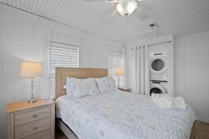 een witte slaapkamer met een bed en een wasmachine en droger bij Beachside Cottage - Pet Friendly in Oak Island