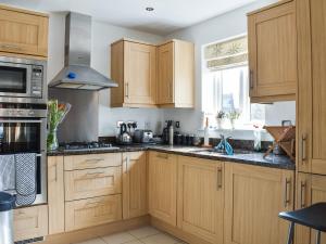 a kitchen with wooden cabinets and a stove at Lime Court - Cottages in Leatherhead