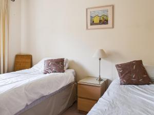 a bedroom with two beds and a night stand with a lamp at Lime Court - Cottages in Leatherhead