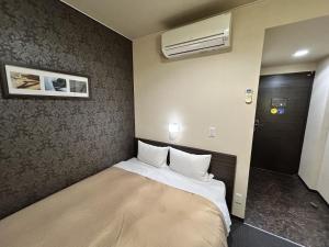 a small bedroom with a bed in a room at Smile Hotel Kokura in Kitakyushu