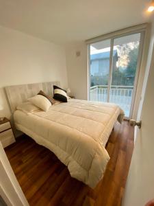 a large bed in a bedroom with a large window at Departamento en Pucón in Pucón