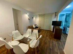 a living room with a glass table and white chairs at Departamento en Pucón in Pucón