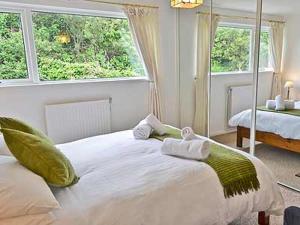 a white bedroom with two beds and two windows at Sheerwater in Appledore