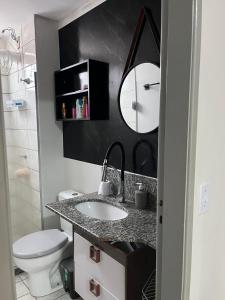 une salle de bain avec un lavabo, des toilettes et un miroir dans l'établissement Apartamento em Vila Velha, à Vila Velha