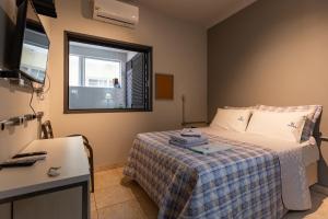 a bedroom with a bed and a desk and a window at K3 Residence Copa & Cozinha in Campinas
