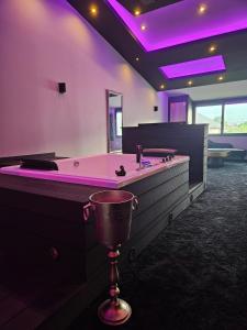 Love Room Le Jardin D'Éden في لاموت سيرفولكس: حمام كبير مع حوض استحمام مع إضاءة أرجوانية