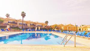 une grande piscine avec des chaises et des transats bleus dans l'établissement Algarver I - Boavista Golf Fairview SwimPool Villa, à Lagos