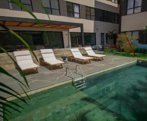 a swimming pool with lounge chairs and a building at FLAT NOVO e ACONCHEGANTE in Ribeirão Preto