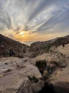a group of people walking on the beach at sunset at Tamri Dar Taous in Tamri
