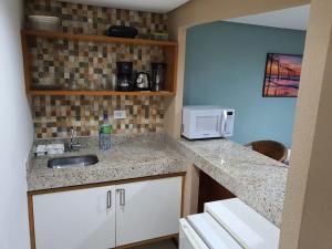 a kitchen with a sink and a microwave at Apartamento Praia do Centro Pipa in Pipa