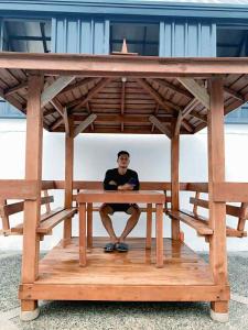 a man sitting on a wooden bench under a pavilion at Yanis Resort in Calatagan