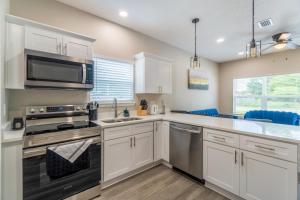 a kitchen with white cabinets and stainless steel appliances at Brand New Modern Luxury Duplex EV Ready in Pensacola +14 photos