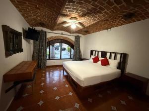 a bedroom with a white bed and a brick wall at Hotel Hacienda Tonalmain, Central Nueva in Guadalajara