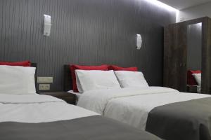 1 dormitorio con 2 camas con sábanas blancas y almohadas rojas en Studio rooms on the 2nd Floor, en Ereván
