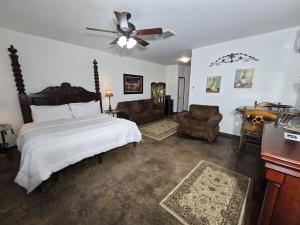 a bedroom with a bed and chairs and a ceiling fan at Fredericksburg Escape Wineries & Hot Tub in Fredericksburg +42 photos