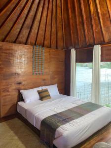 a bed in a room with a wooden ceiling at Alang Cottage in Masbagik