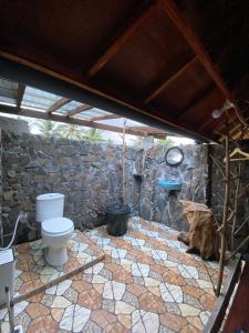 a bathroom with a toilet and a stone wall at Alang Cottage in Masbagik