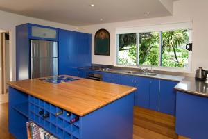 a kitchen with blue cabinets and a wooden counter top at The Lookout - great views in Muriwai Beach