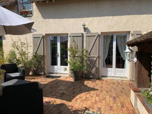 patio z białymi drzwiami i ceglaną podłogą w obiekcie La Meunière w mieście Jouy