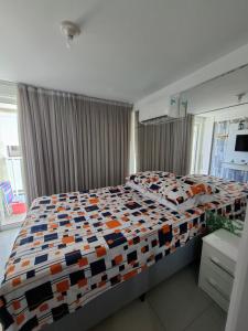 a bedroom with a large bed with a colorful comforter at Flat vista mar de Intermares completíssimo 508 in João Pessoa +59 photos