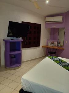 a bedroom with a bed and a tv on a wall at Cerezas in Cancún