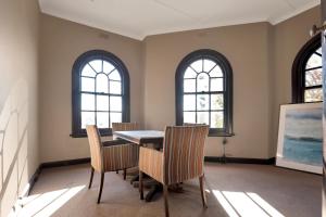 a dining room with a table and chairs and two windows at Hotel Warrnambool in Warrnambool