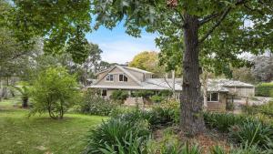 ein Haus mit einem Baum im Hof in der Unterkunft Southrose Cottage in Moss Vale