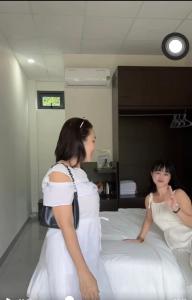 Buôn ÐũngHomestay Buôn Mê 4的两个女人坐在房间里的床边