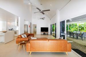 an open living room with a couch and a tv at Serenity Villa with heated POOL & Beach access in Port Douglas