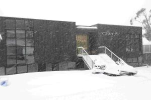 a snow covered bench in front of a building at Konayuki Apartment 4 in Falls Creek