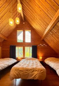 1 Schlafzimmer mit 2 Betten in einer Holzhütte in der Unterkunft 一棟まるっと温泉別荘 天井高7ｍ 50インチ映画見放題 屋根付BBQ 街まで車7分 湯布院30分 アニメ聖地10分 in Tsukawaki