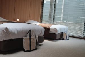 a hotel room with two beds and luggage at Law Firm ローファーム in Nagano