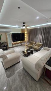 a living room with two white couches and a tv at One Euphoria Luxe Hotel in Angeles