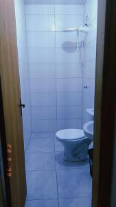 a white bathroom with a toilet and a sink at Apartamento Mobiliado in Guaíba