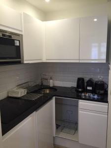 a kitchen with white cabinets and a black counter top at Bellechasse Apartments in Paris