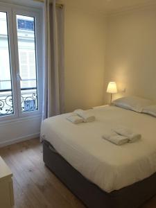 - une chambre avec un grand lit blanc et une fenêtre dans l'établissement Bellechasse Apartments, à Paris