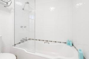 a white bathroom with a tub and a shower at Magnolia on Colville - Historic Riverside Elegance in Hobart